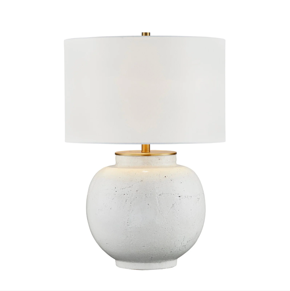 Table lamp with a white textured base and gold accents on a white background