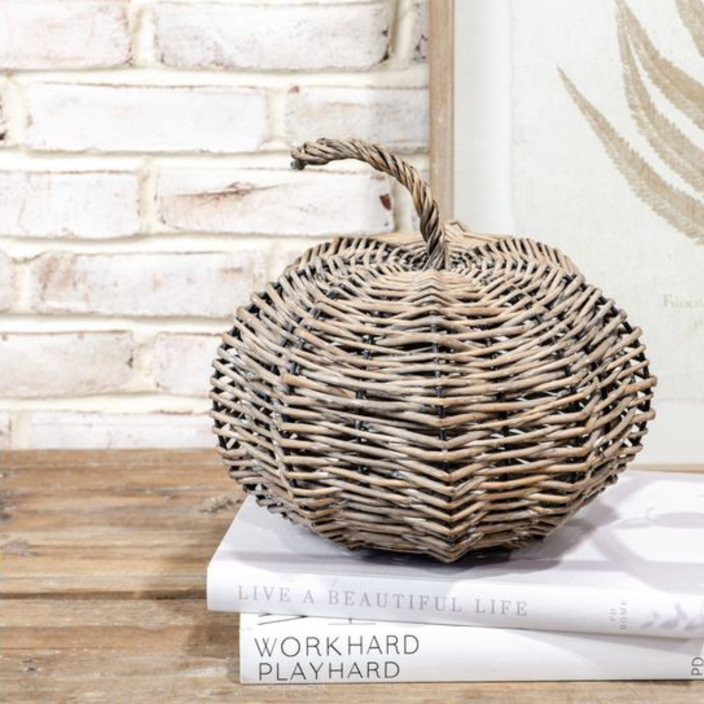 Wicker pumpkin on top of books with a white brick wall background