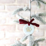 Decorative ornament with paw print design hanging on a Christmas tree.