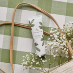 Hand cream tube with greenery design on a checkered fabric background