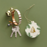 Keychain with bell and keys next to a Christmas ornament on a green background