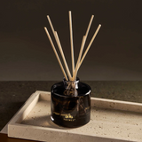 Black diffuser with wooden sticks on a concrete surface