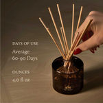 Hand holding a diffuser stick with product details on a wooden background
