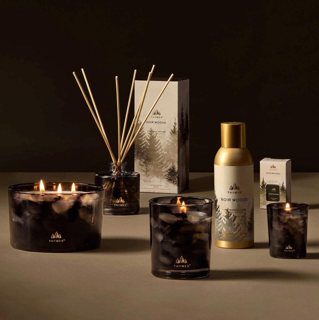 Thymes Noir Wood candles, diffuser, and packaging on a dark background