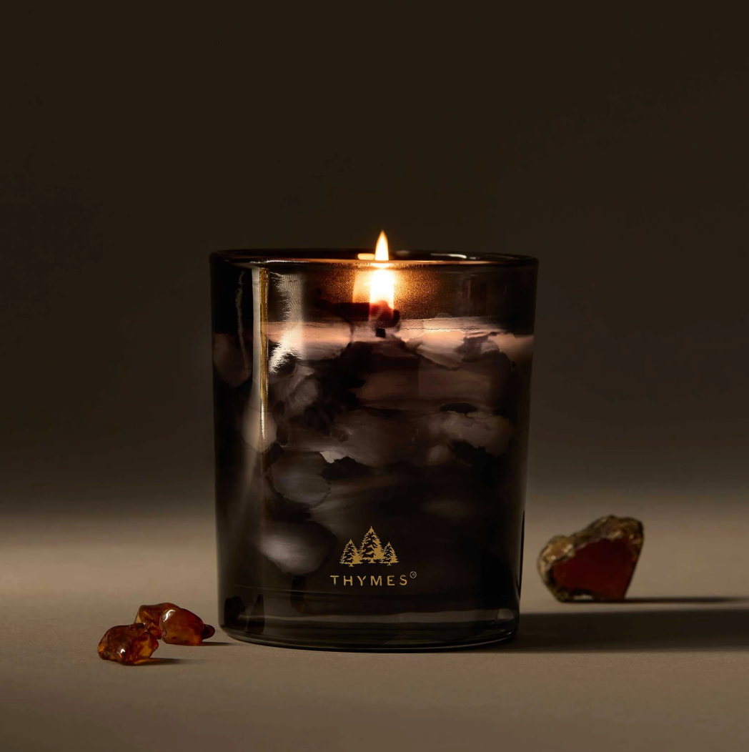 Thymes candle in a dark glass container with a blurred background