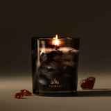 Thymes candle in a dark glass container with a blurred background