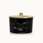 Black marbled candle jar with gold lid on a white background, featuring the Thymes logo.