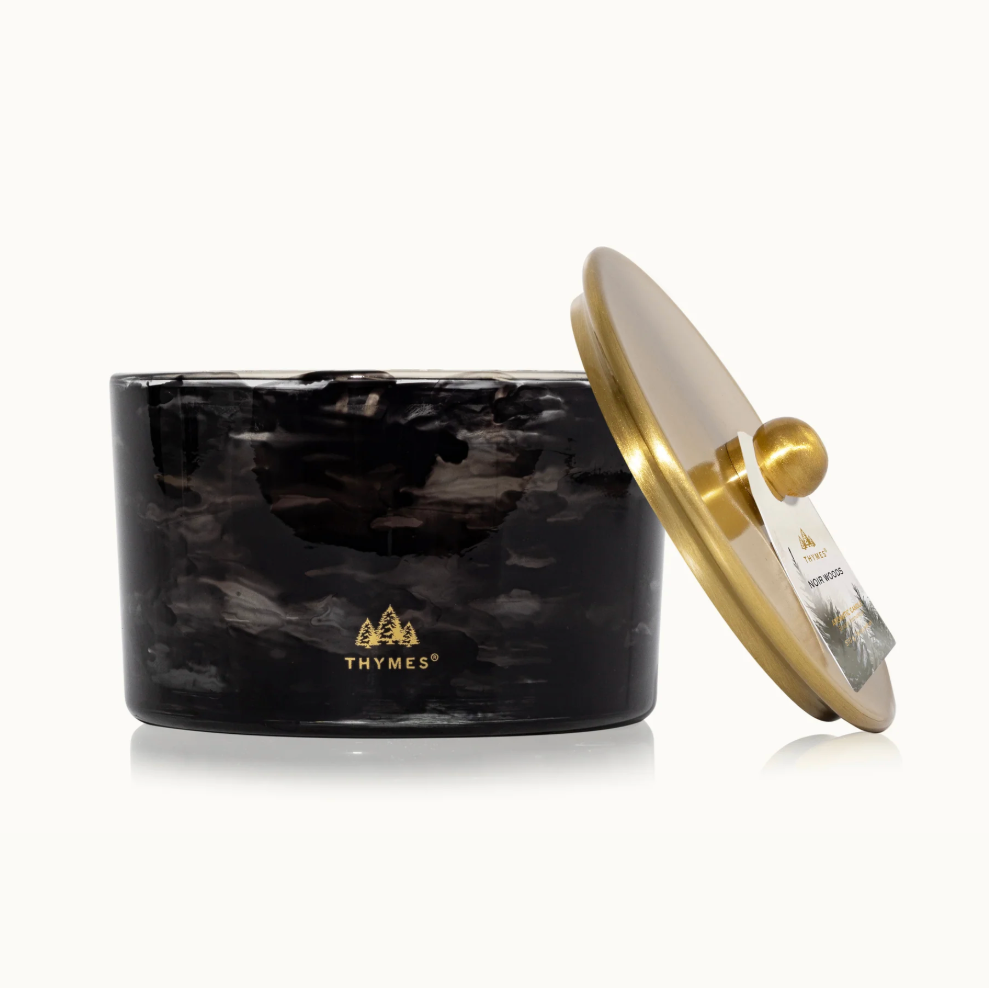 Black marbled candle with a gold lid on a white background, featuring the Thymes logo.