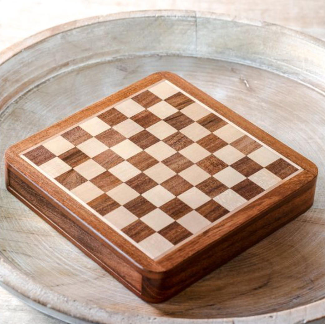 Wooden chess board with checkered pattern on a wooden surface
