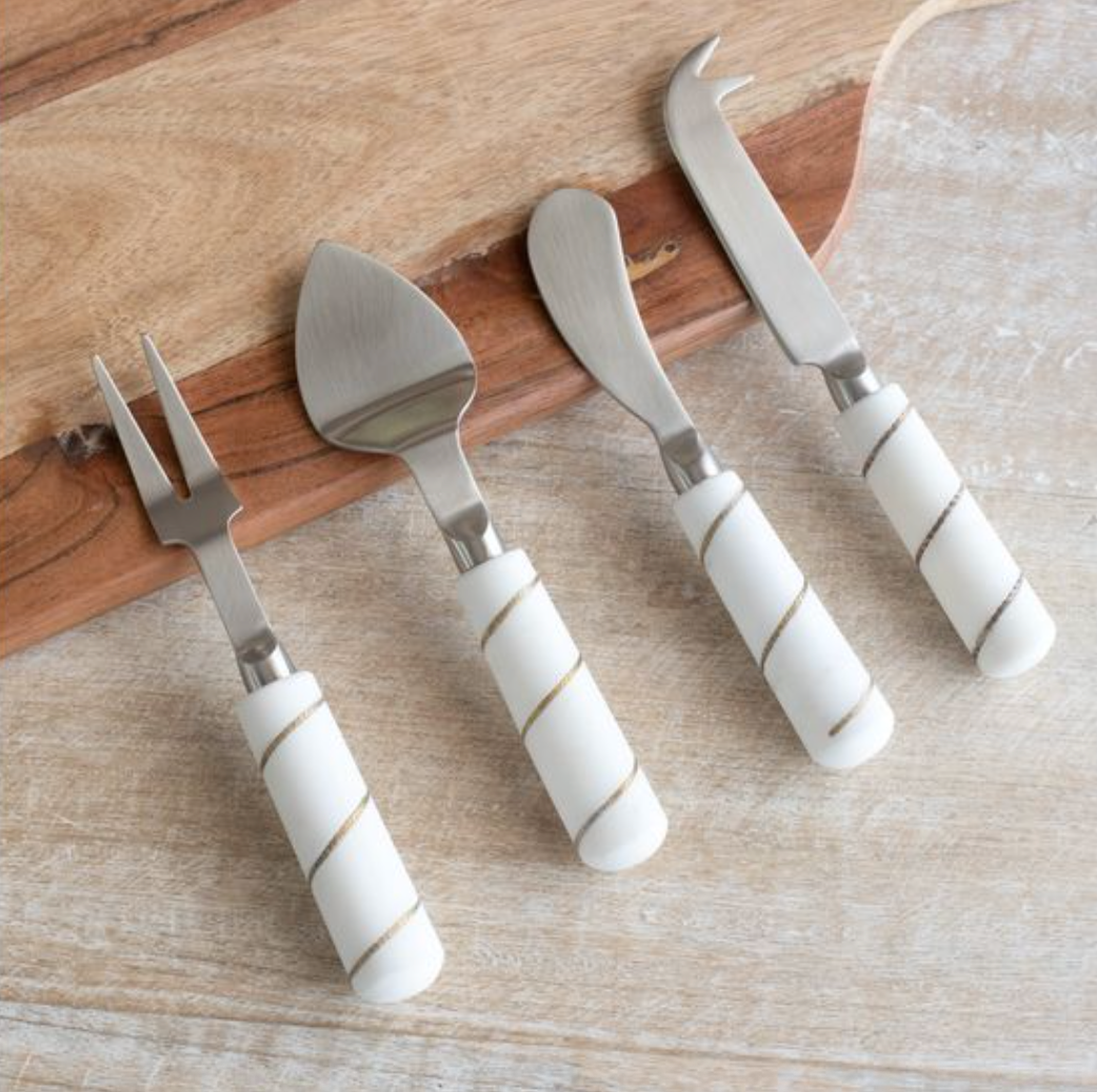 Set of four cheese tools with white marble handles on a wooden surface