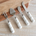 Set of four cheese tools with white marble handles on a wooden surface