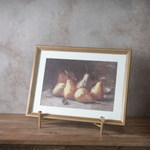 Framed artwork of pears on a wooden surface with a textured wall background