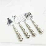 Set of four silver serving set with beaded handles on a white background
