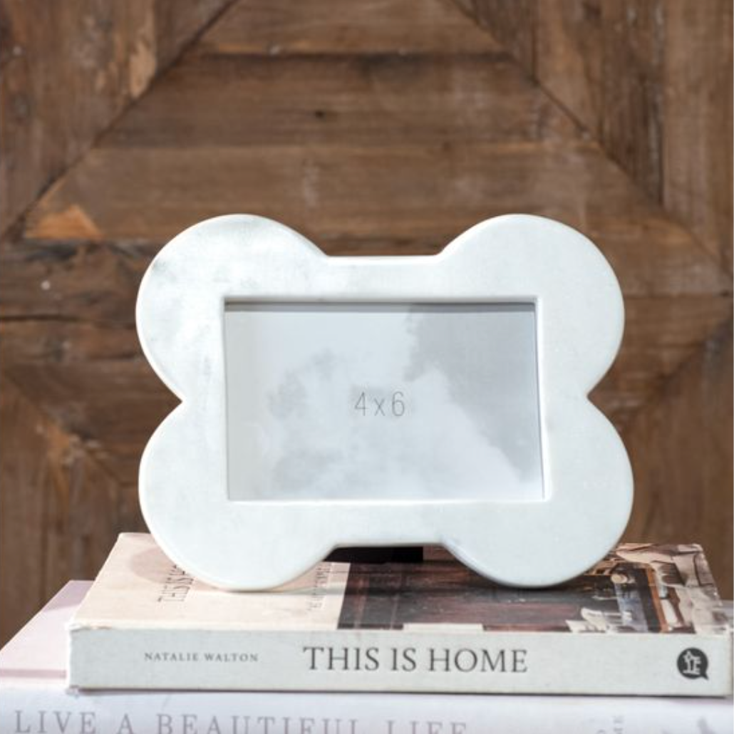 White bone-shaped photo frame on a book with a wooden background