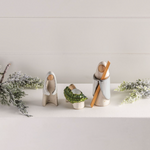 Decorative items including small trees and wooden figures on a light surface with a neutral background