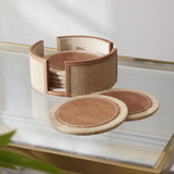 Set of brown coasters with a woven holder on a glass surface.