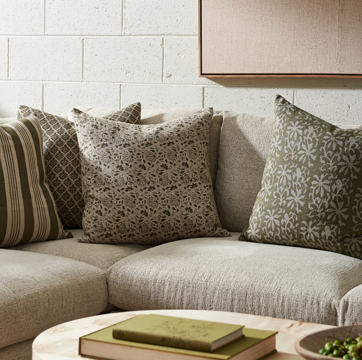 Gray sofa with patterned cushions against a light brick wall.