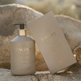 L'avant Collective hair care bottle and its matching box displayed outdoors on a rocky surface with a blurred natural background.
