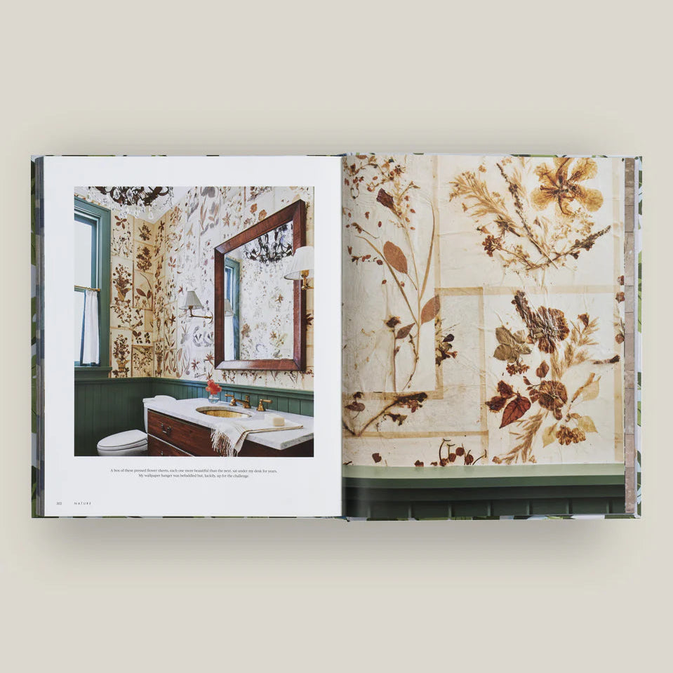 Open book showing a bathroom interior with floral wallpaper on a white background