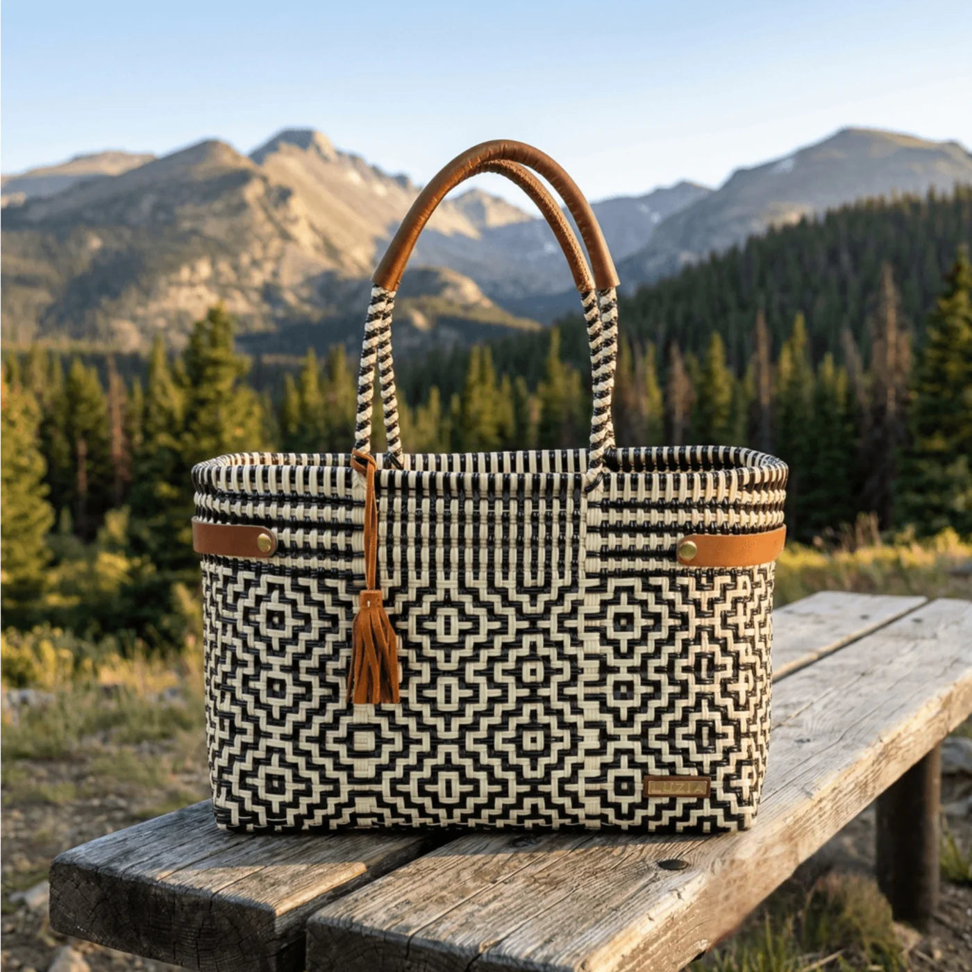 Woven bag with geometric pattern on a wooden bench in a mountainous landscape