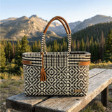 Woven bag with geometric pattern on a wooden bench in a mountainous landscape