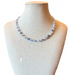 Blue beaded necklace on a mannequin bust with a blurred background