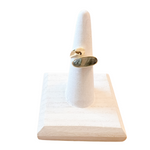 Gold ring with a stone on a white marble stand