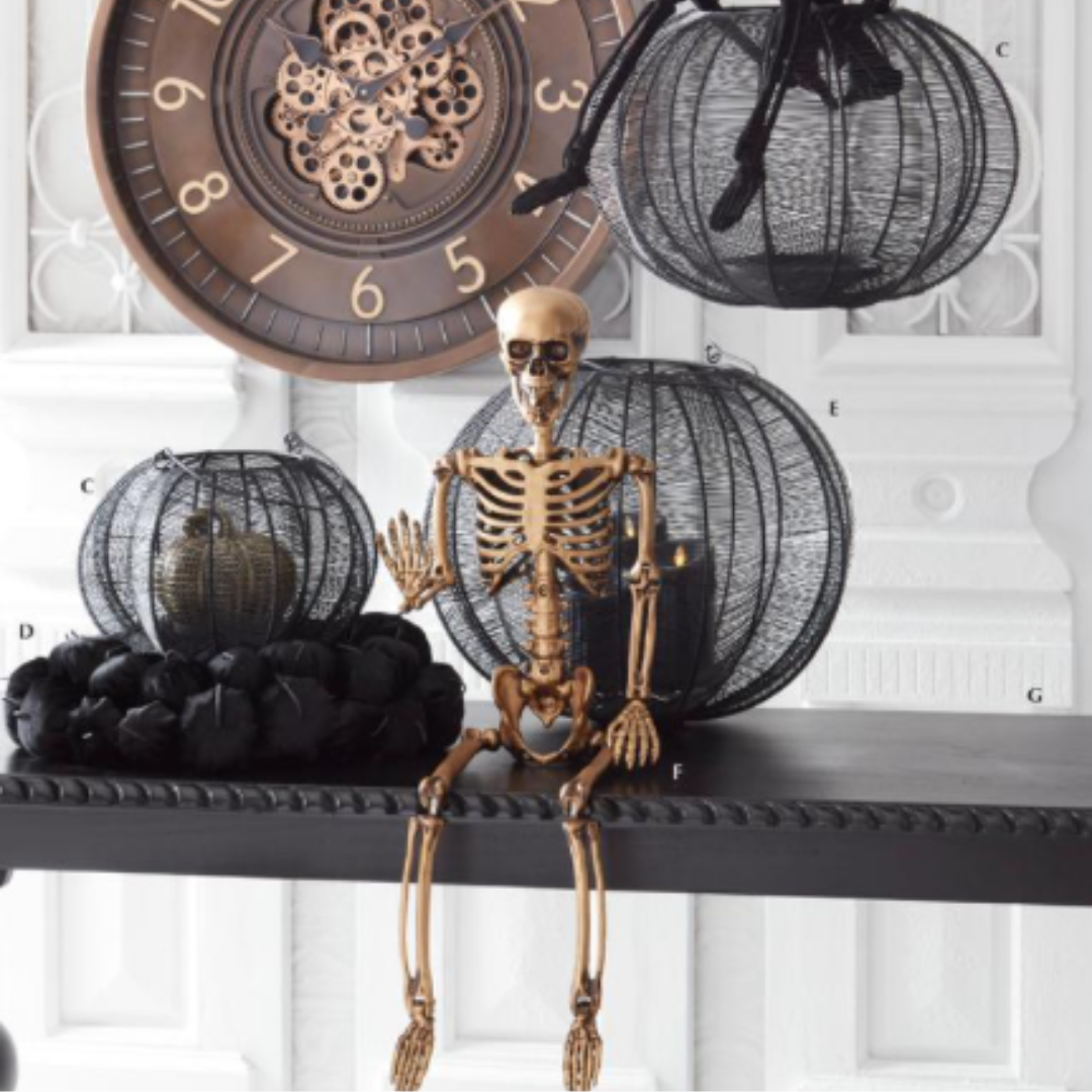 Halloween-themed decor with skeleton figure, black wire pumpkins, and clock on a white background
