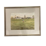 Framed artwork of a person playing golf on a grassy field with buildings in the background.