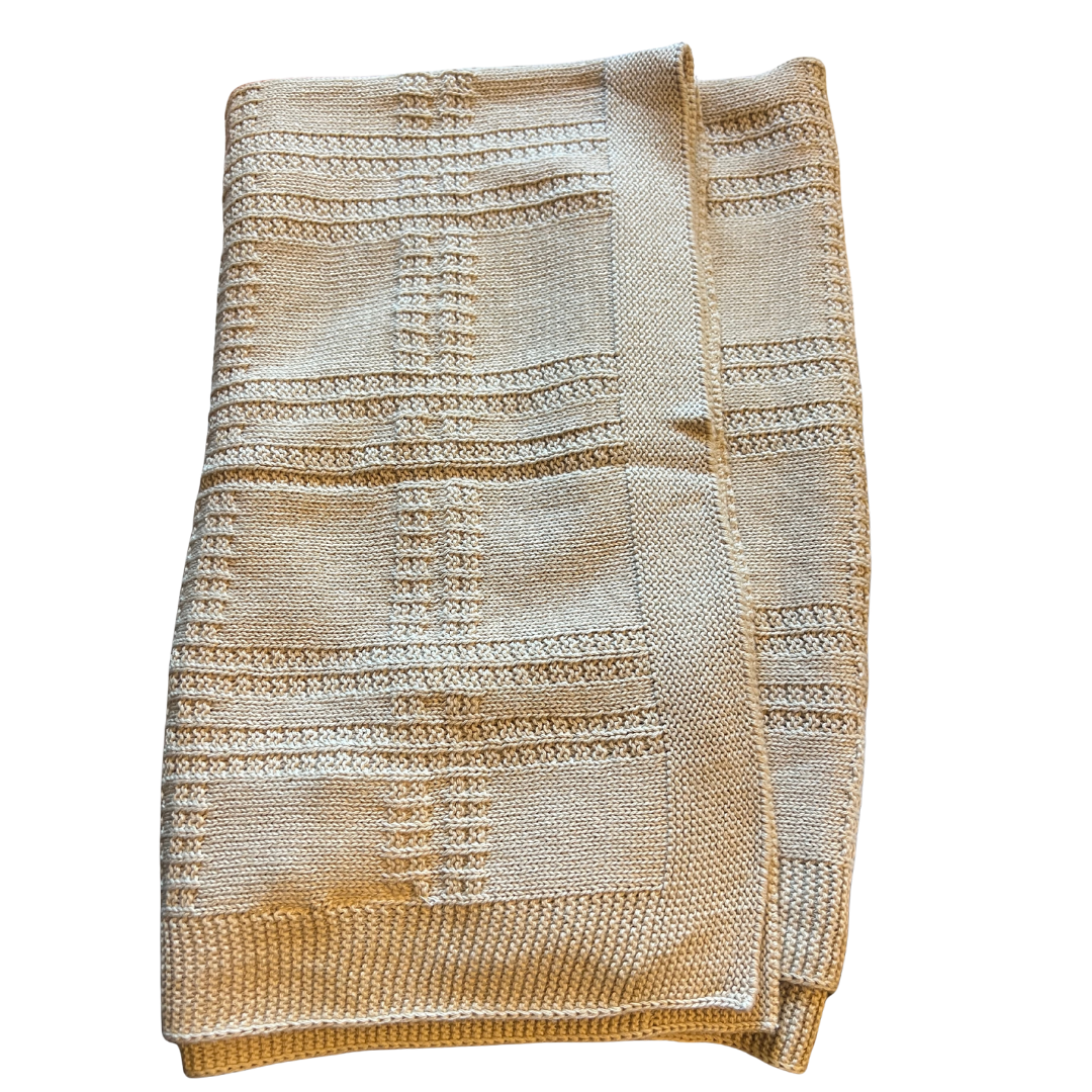 Neutral beige cotton knit baby blanket with a plaid-inspired textured pattern and ribbed border, folded neatly on a white background.