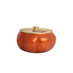 Pumpkin-shaped container with gold lid on a white background