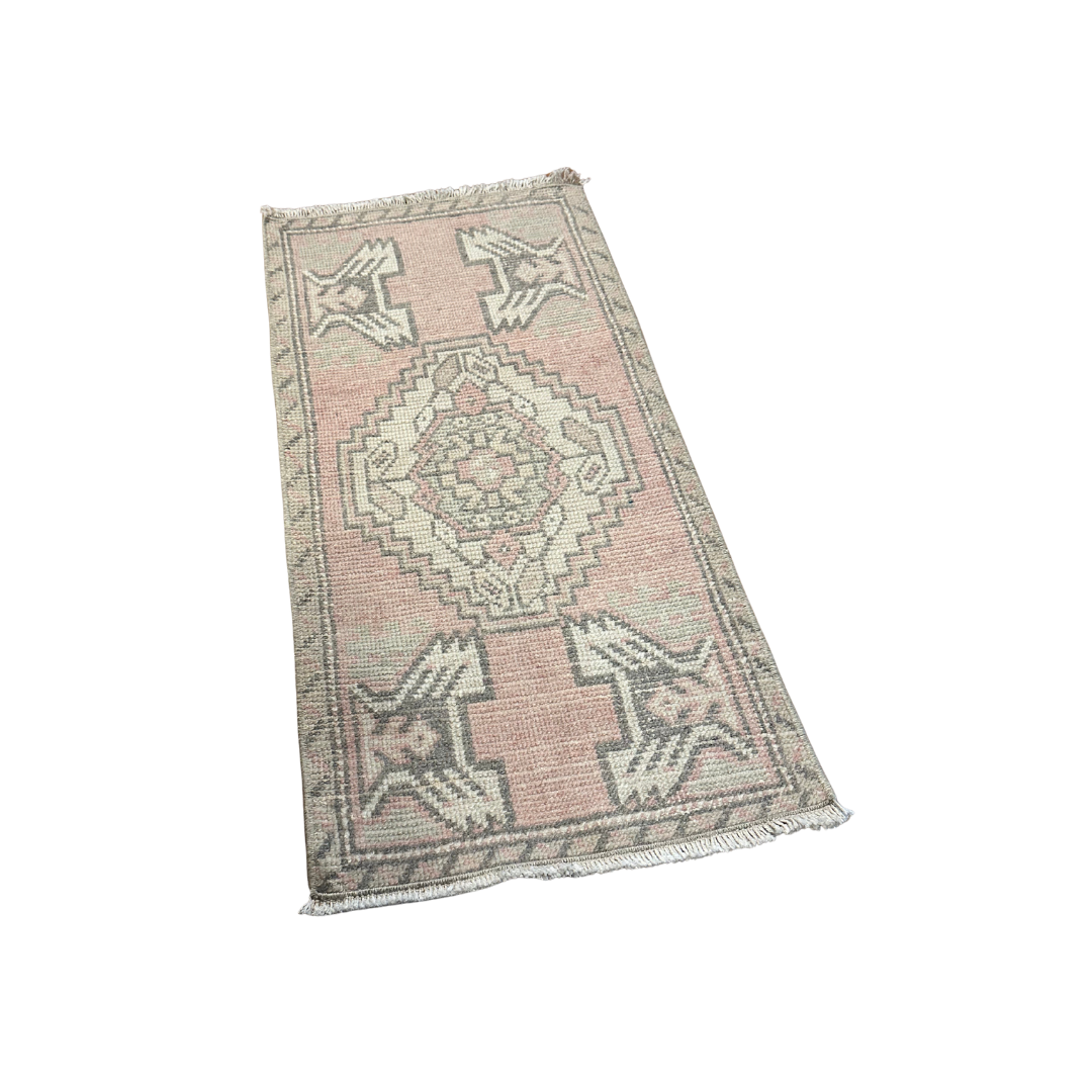 Small pink and white patterned rug on a white background