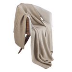 Beige knitted blanket draped over a chair on a white background