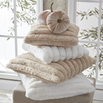 Stack of fluffy towels with decorative pumpkins on a windowsill.