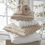 Stack of fluffy towels with decorative pumpkins on a windowsill.