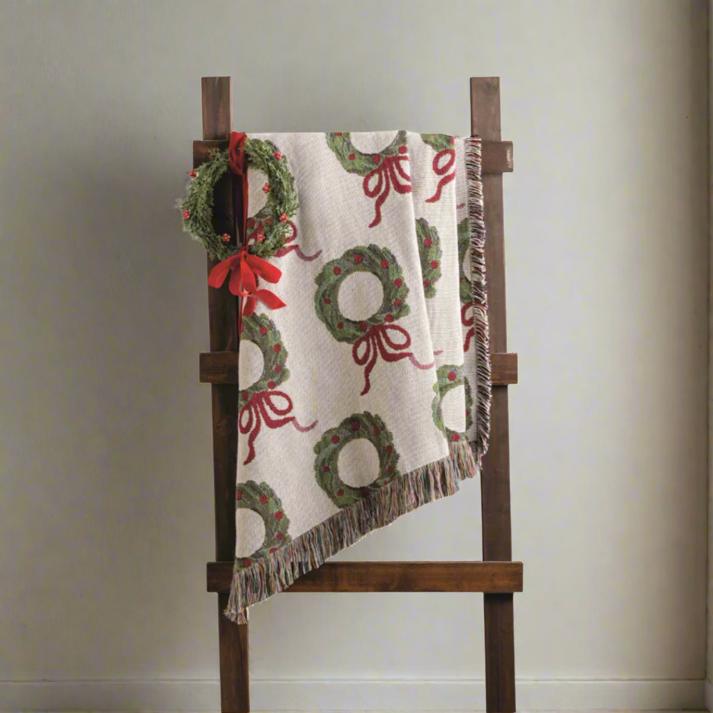 Decorative blanket with wreath and bow pattern on a wooden ladder