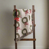 Decorative blanket with wreath and bow pattern on a wooden ladder