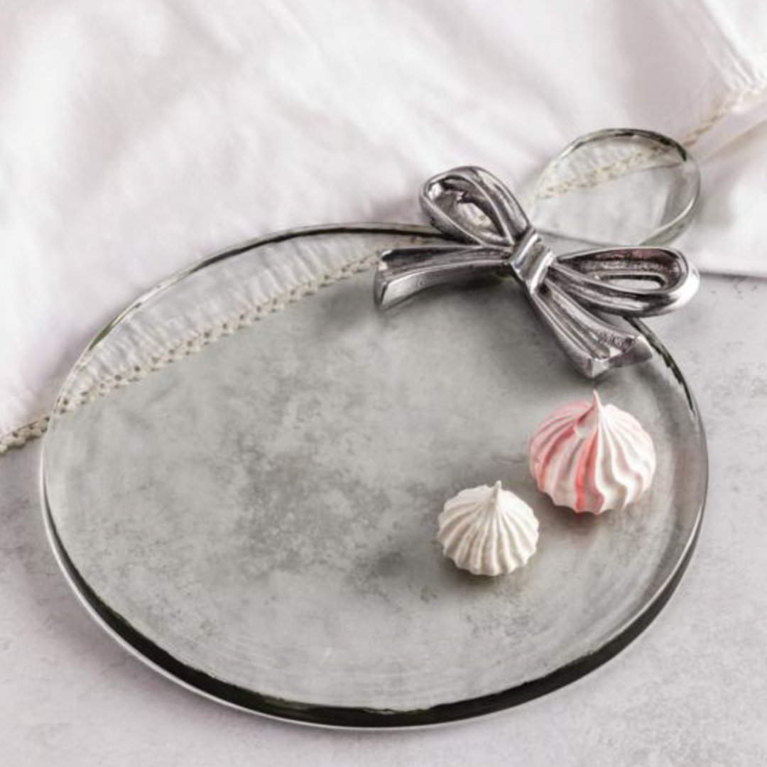 Decorative plate with a silver bow and two small, round, pink and white items on a light background