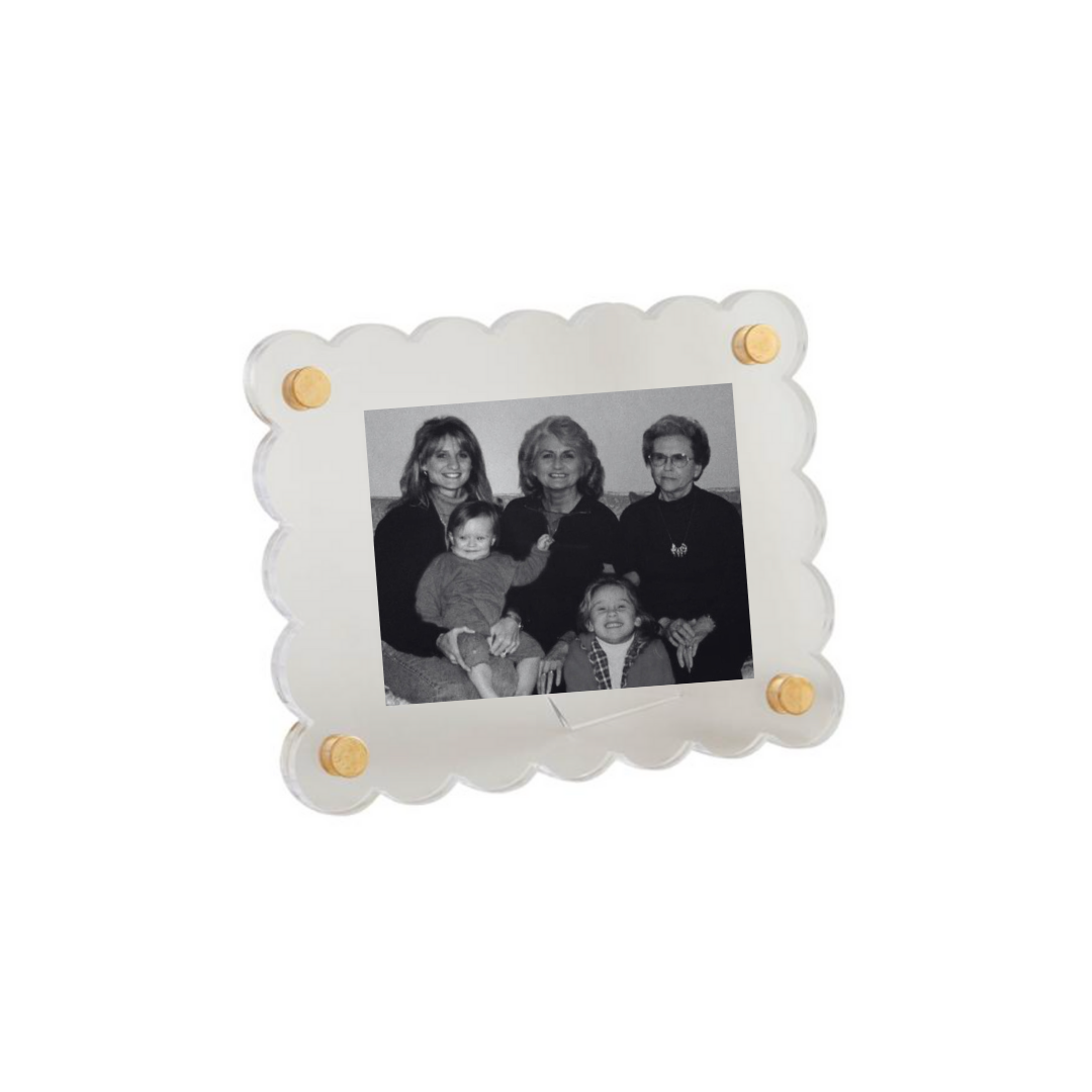 Small white frame with scalloped edges holding a family photo on a white background