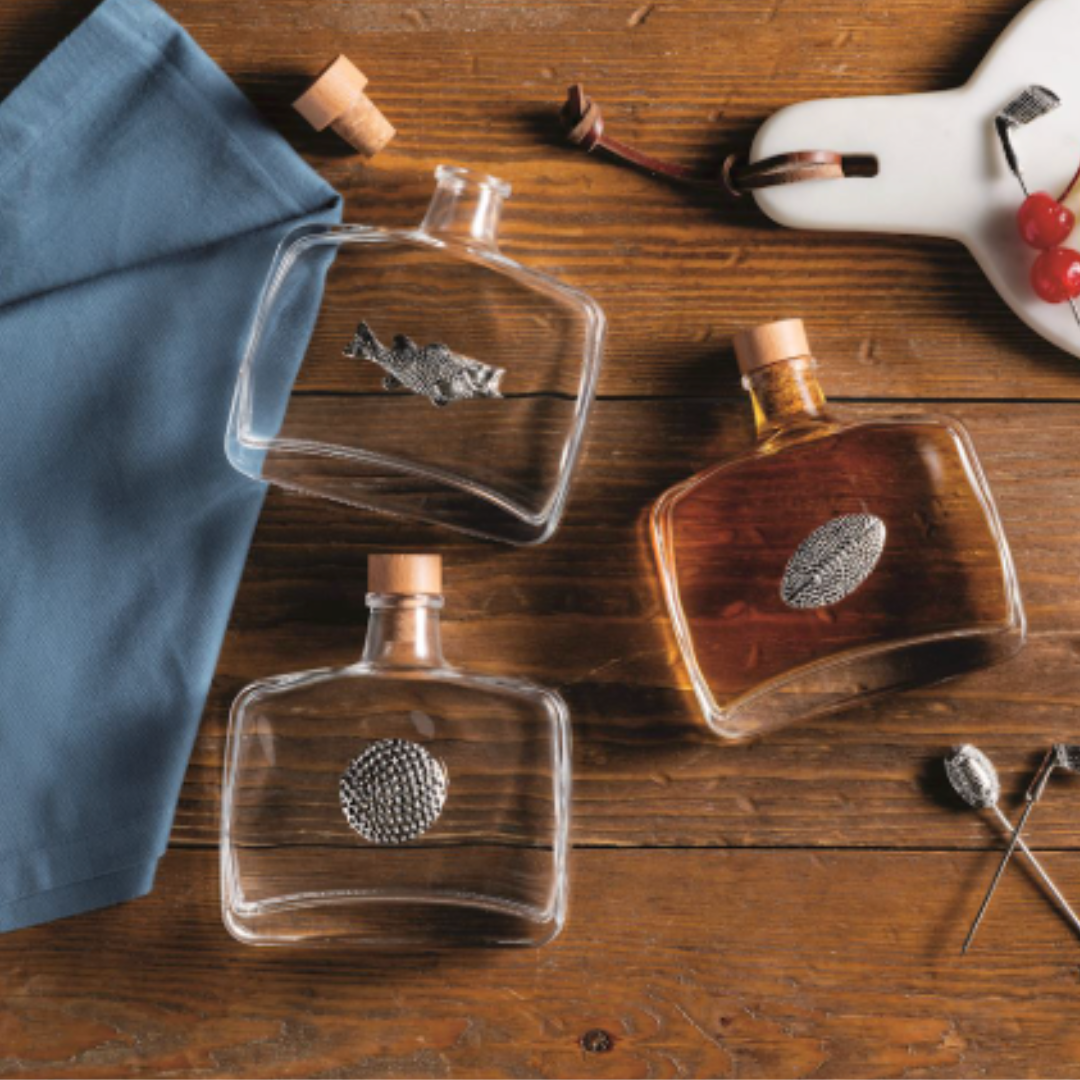 Three bottles of tequila on a wooden surface with a blue towel and decorative items.