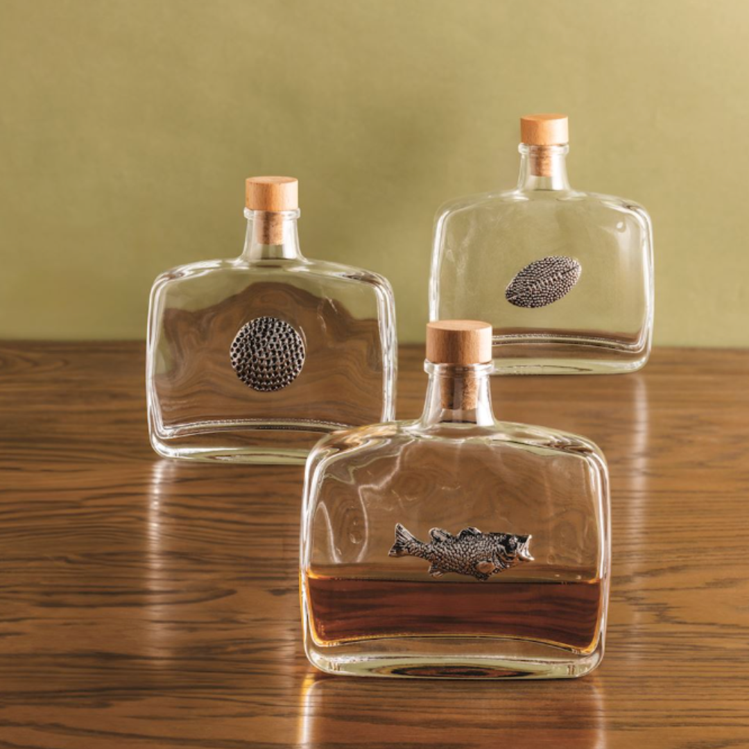 Three glass bottles with fish designs on a wooden surface