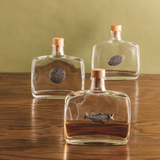 Three glass bottles with fish designs on a wooden surface