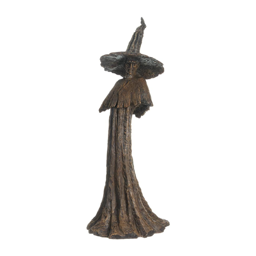 Bronze statue of a witch with a wide hat on a white background