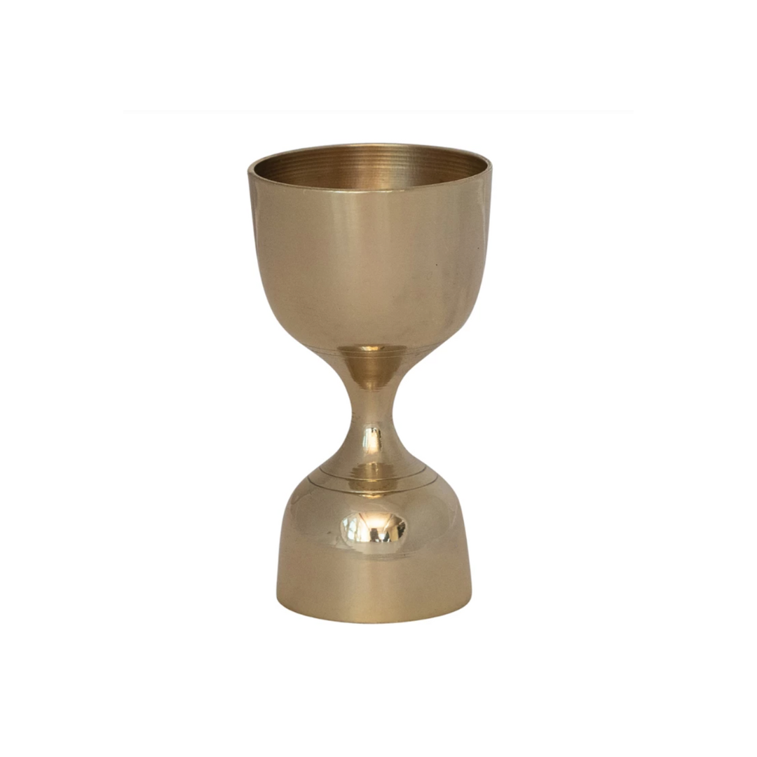 Gold cocktail jigger on a white background