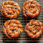 Four braided pastries with a sprinkle of salt on a cooling rack.