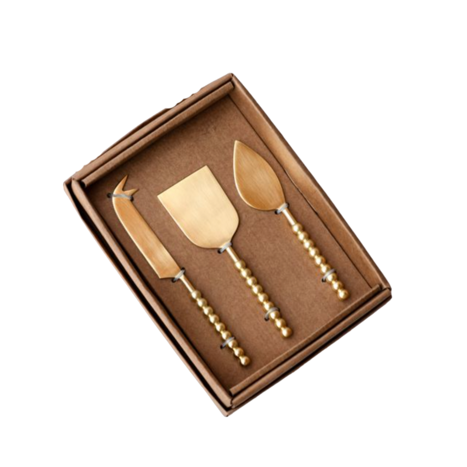 Set of three gold cheese knives in a brown box on a white background