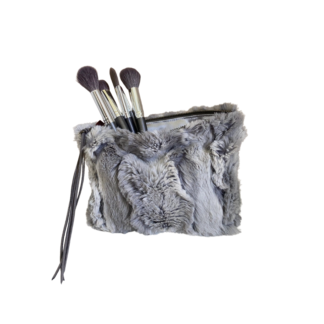 Gray fur makeup bag with brushes on a white background