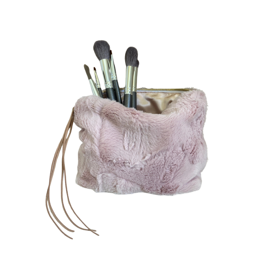 Pink fluffy makeup bag with brushes on a white background