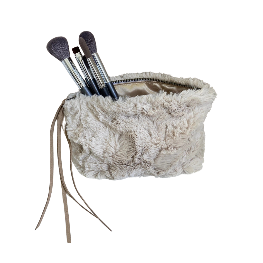 Fluffy beige makeup bag with brushes on a white background