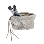 Fluffy beige makeup bag with brushes on a white background